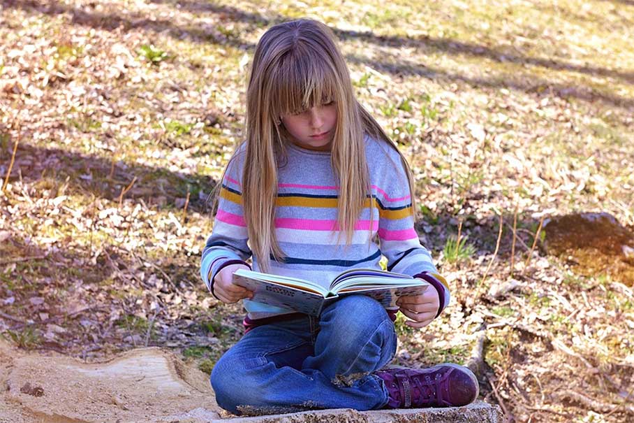 girl with learning disability reading book outside